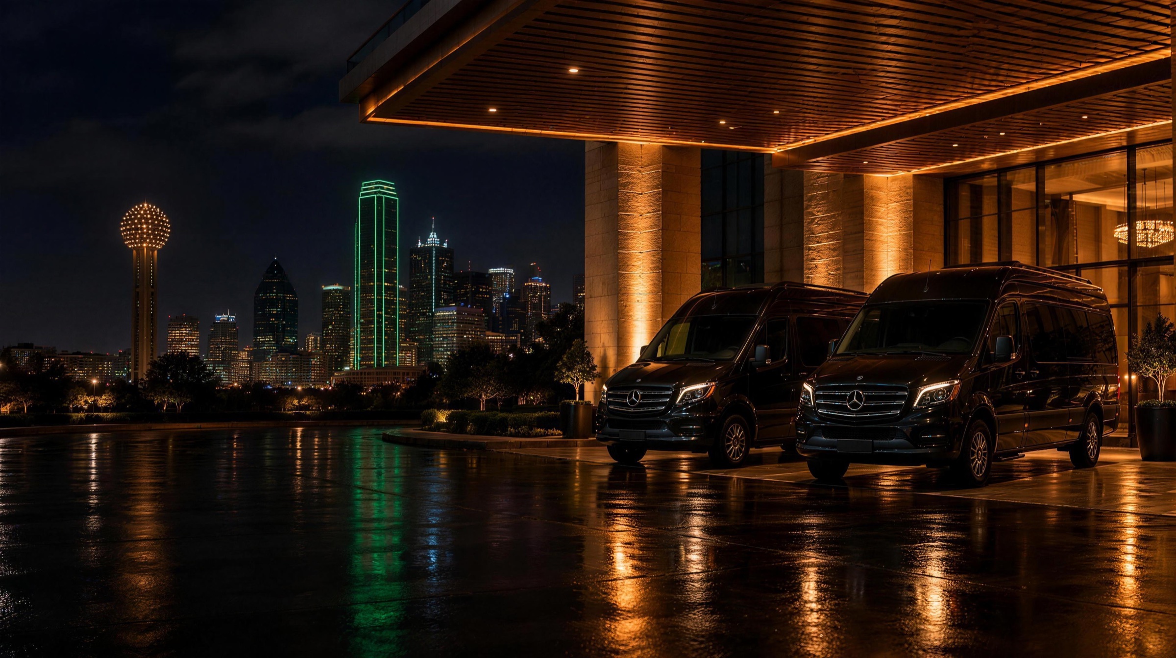 Two black executive Sprinter vans under a Dallas hotel entrance at night with Reunion Tower and the skyline behind